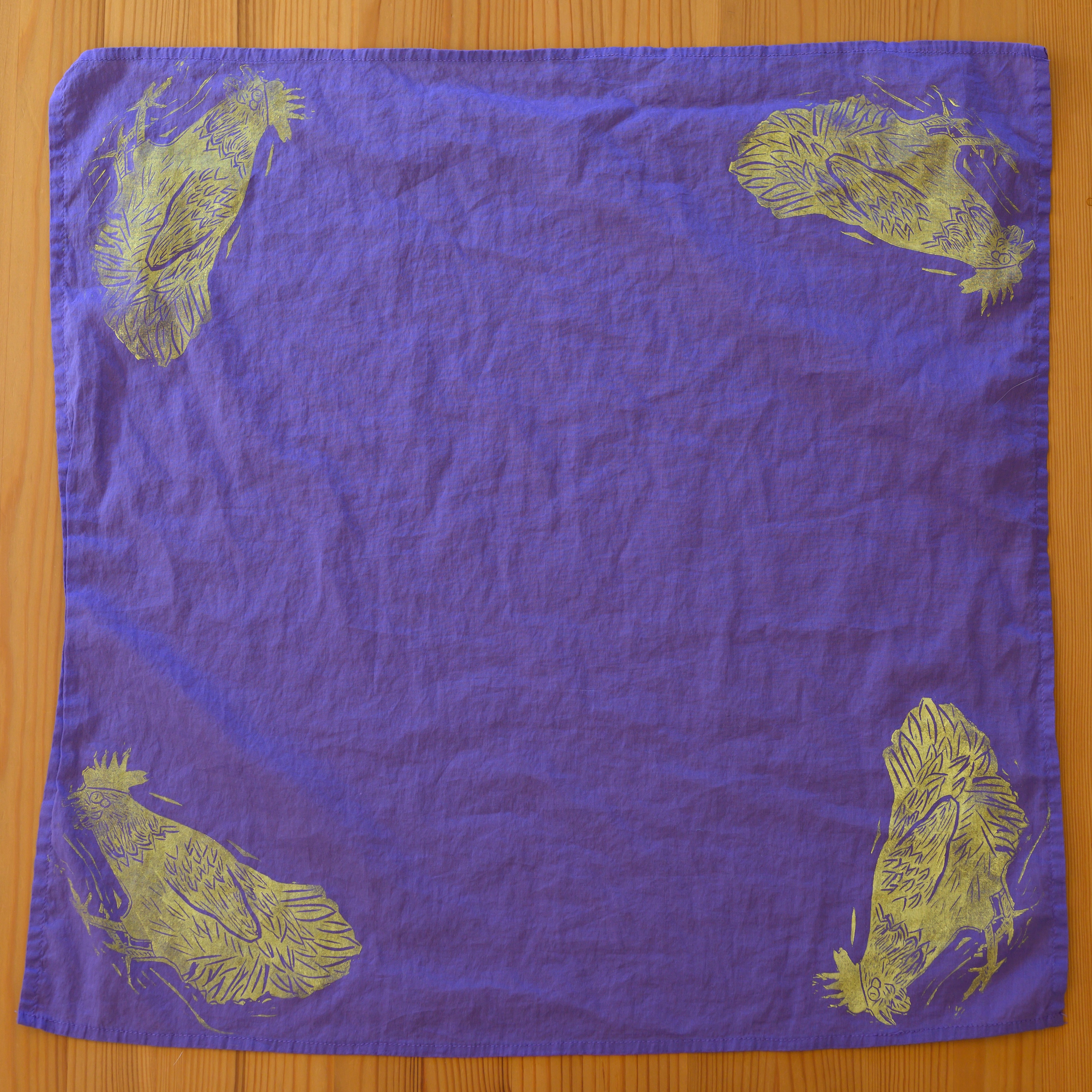 An overview of a purple bandana. There is a light yellow chicken in each corner leaning down, tail in the air.