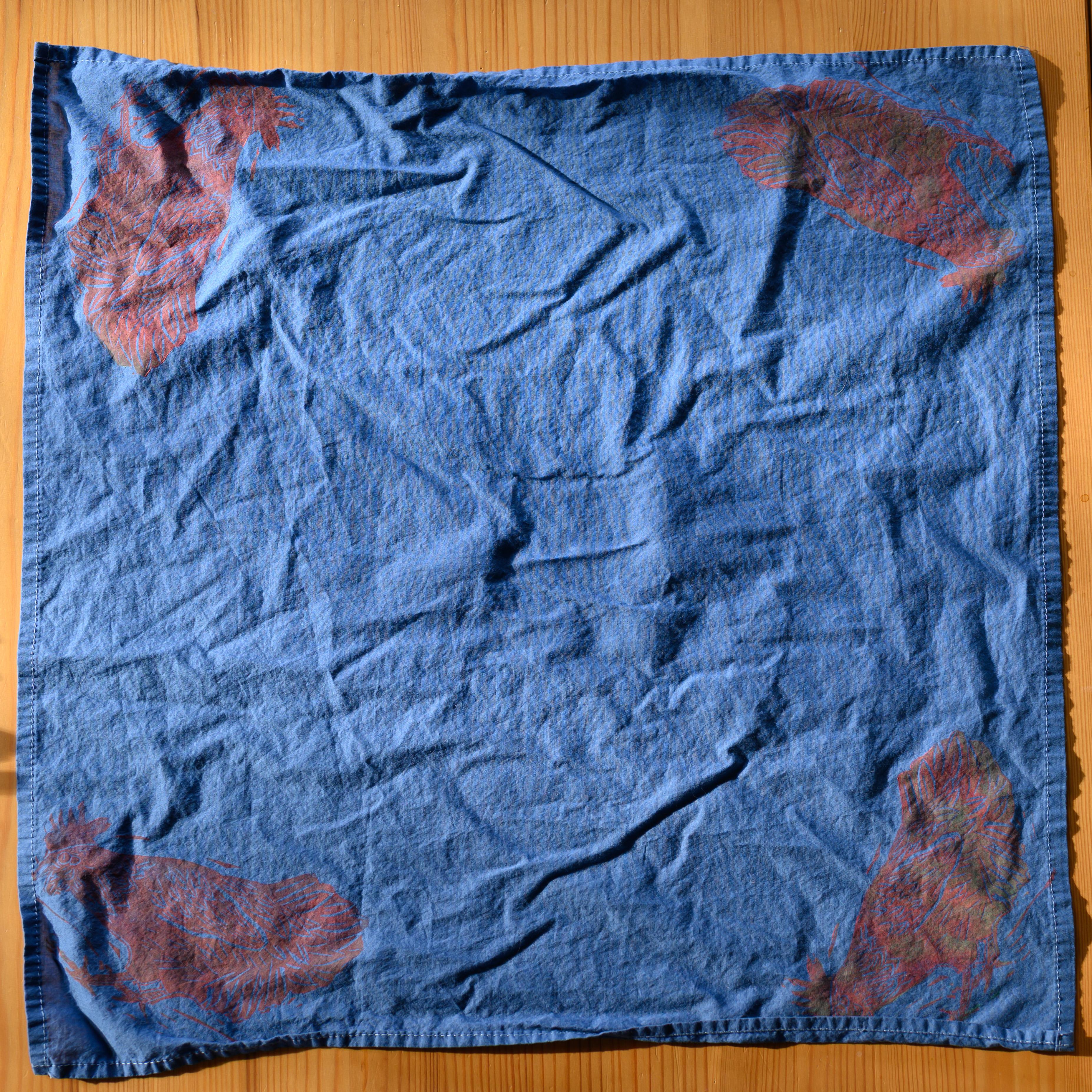 An overview of a navy bandana. There is a red-ish chicken in each corner leaning down, tail in the air.