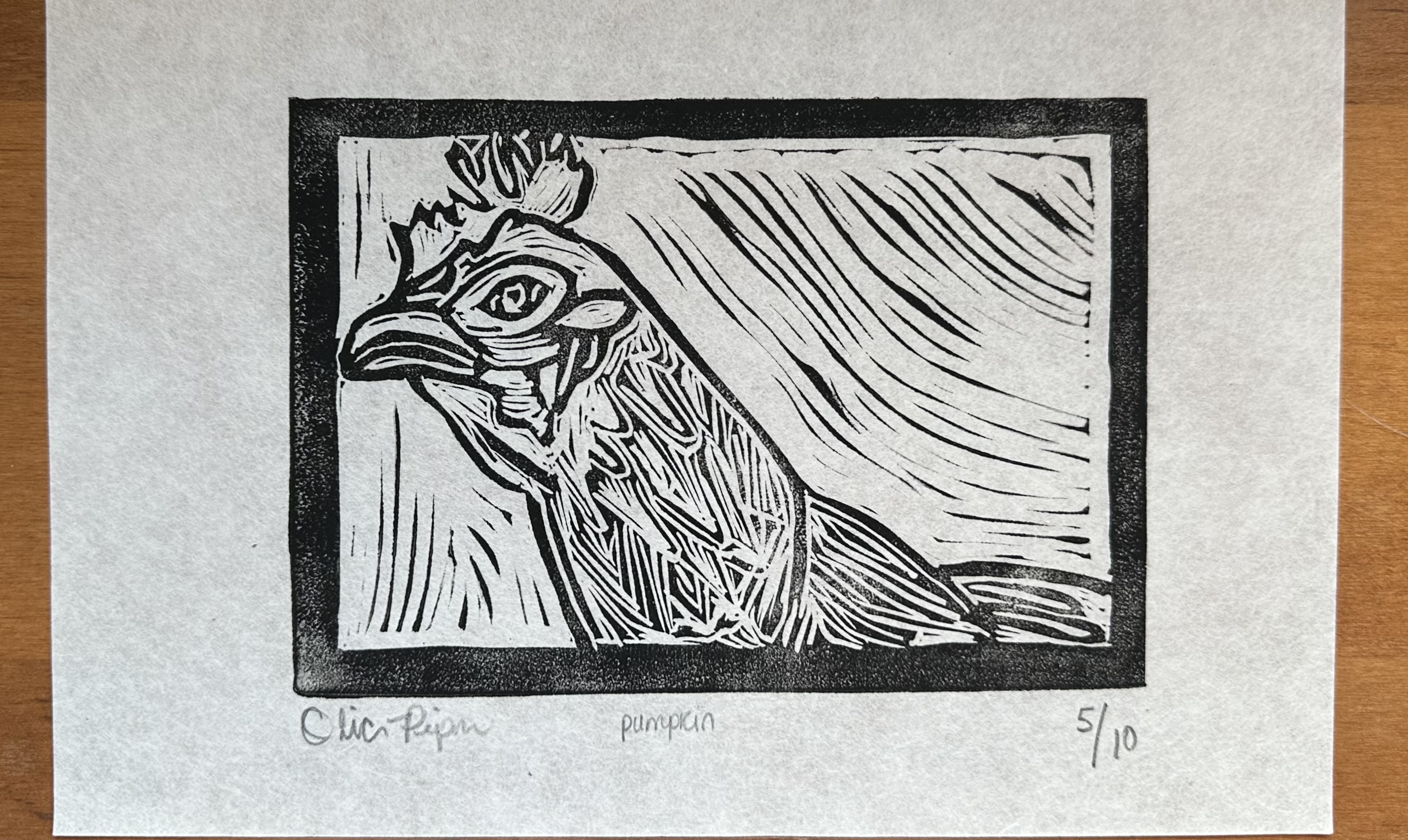block print within a black border of a close up of a chicken from the neck up looking at the viewer. it is signed below the border with "pumpkin" and 5/10