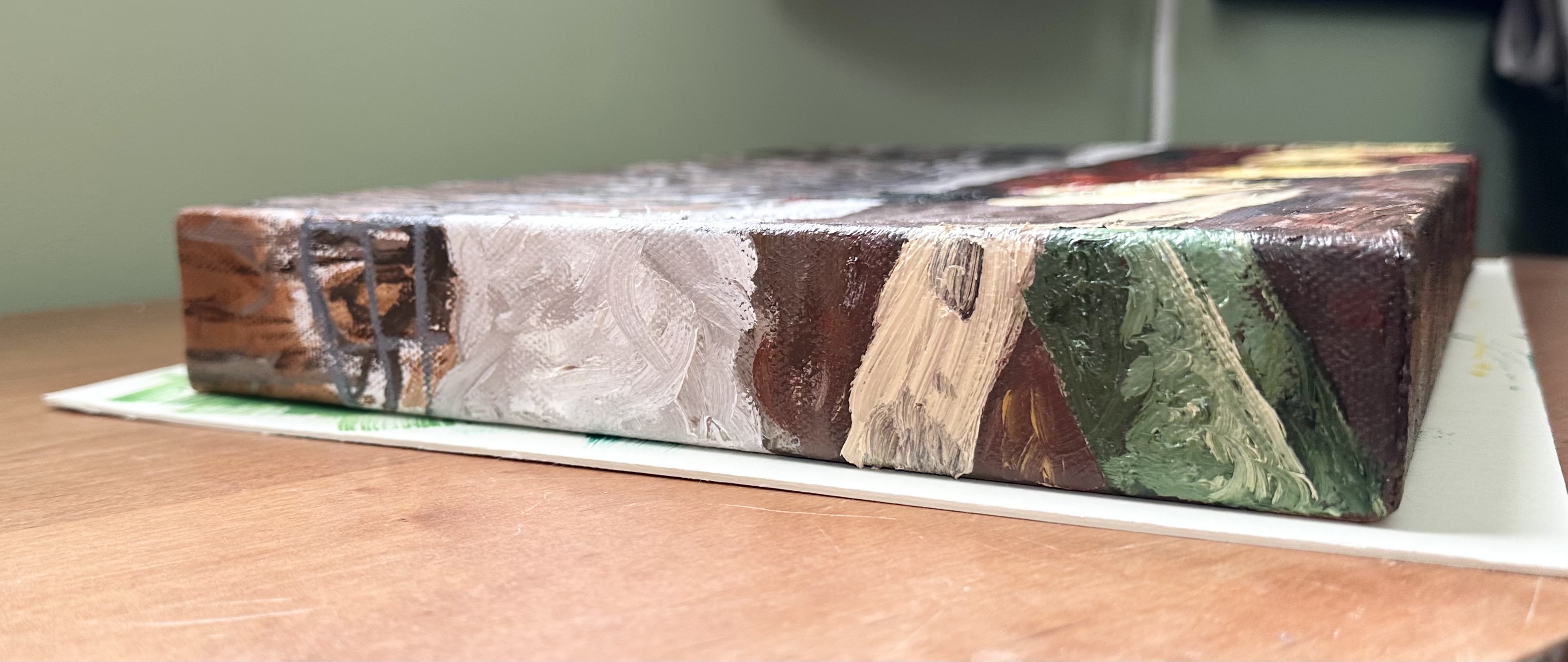 The left side. At the top some woods and snow can be seen, then the rest of the wooden plank with a green slab holding it up.
