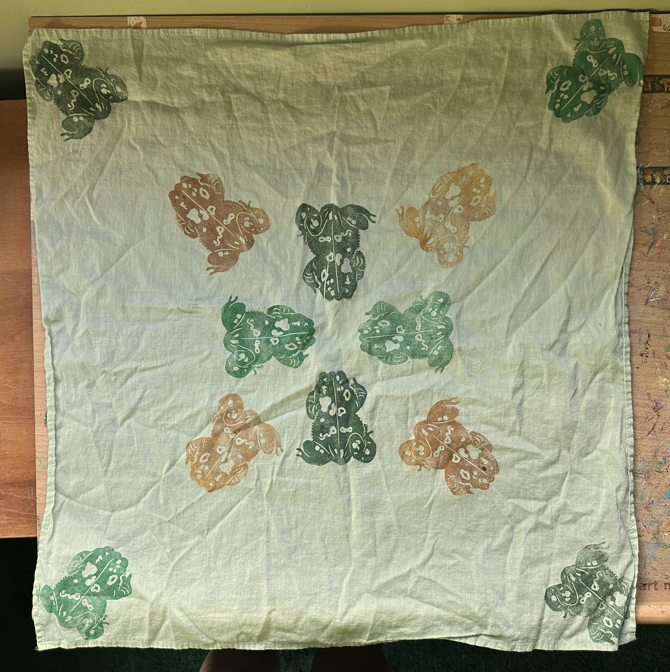 A light green bandana from above. There are toads on it in a sort of pattern in the center and one in each corner.